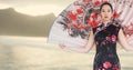 Geisha with giant fan against blurry yellow coastline