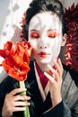 Geisha holding red flowers in sunlight