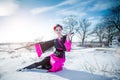 Geisha with katana in black and pink kimomo sitting on the ground on winter landscape background