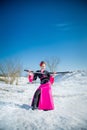 Geisha with katana in black and pink kimomo on winter landscape and blue sky background. Royalty Free Stock Photo