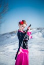 Geisha with katana in black and pink kimomo on winter landscape and blue sky background. Royalty Free Stock Photo