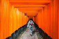 Geishas among red wooden Tori Gate at Fushimi Inari Shrine in Ky