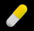 A gelatin capsule with yellow cap isolated on black background closeup Royalty Free Stock Photo