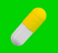 A gelatin capsule with yellow cap isolated on green background closeup Royalty Free Stock Photo