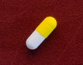 A gelatin capsule with a yellow cap on a red background Royalty Free Stock Photo