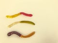 Gelatinous worms of different colors lie on a yellow matte background. gummy candies in the form of long worms of bright color. Royalty Free Stock Photo