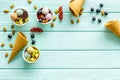 Gelato, waffle cone, berries, chocolate, hazelnut on mint green wooden background top view copyspace