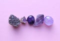 Gemstone minerals on a pink background. Round tumbling minerals of amethyst and amethyst crystal