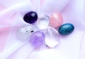 Gemstone minerals on a pink background. Round tumbling minerals of amethyst, rose quartz, rock crystal and apatite on white