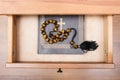 Gemstone rosary on Bible book in open drawer