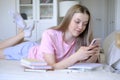 A young girl 15-18 years old lies on the bed with a phone in her hands. Royalty Free Stock Photo
