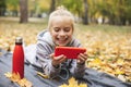 Gen z teenage girl using smartphote outdoors in autumn time.