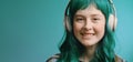 Gen Z teenager with green hair listens music in headphones. Music subscription service concept.