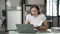 Gen Z young student girl in headphones studying internet at laptop Listen to audio narration Webinars Writing notes,