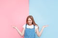 Gender of the child. Young pensive pregnant woman standing on a pink and blue background