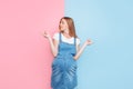 Gender of the child. Young pensive pregnant woman standing on a pink and blue background