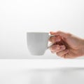 And gender holds a plain white ceramic mug by the handle set against Royalty Free Stock Photo