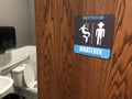 Gender inclusive restroom sign on partially open wooden toilet door Royalty Free Stock Photo