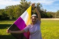 Gender non-binary person is holding the flag of non-binary pride in his hands in the wind. He is looking at the camera. Concept of Royalty Free Stock Photo