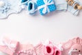 Top view photo of pink and blue infant clothes shirts pants knitted booties gift boxes bunny rattle toy and teether chain