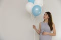 Gender reveal party. Pregnant woman holding blue and white balloons