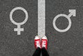 Gender symbols of love on asphalt background. Selfie feet and red sneaker shoes with male and female white sign on road.