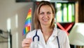 Gender tolerant female doctor smiles holding rainbow flag