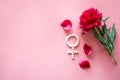 Gender Venus symbol made of pills, and peony flower on a pink background.