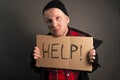 The general plan of the homeless man holding a cardboard with the inscription in his hands asks for help Royalty Free Stock Photo