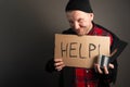 The general plan of the homeless man holding a cardboard with the inscription in his hands asks for help Royalty Free Stock Photo