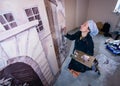 Woman artist working on wall painting, kneeling.