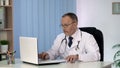 General practitioner putting patient data in electronic medical record on laptop