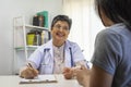 General practitioner taking notes when talking to female patient in hospital. Royalty Free Stock Photo