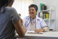 General practitioner taking notes when talking to female patient in hospital. Royalty Free Stock Photo