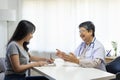 General practitioner taking notes when talking to female patient in hospital. Royalty Free Stock Photo