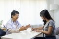 General practitioner taking notes when talking to female patient in hospital. Royalty Free Stock Photo