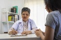 General practitioner taking notes when talking to female patient in hospital. Royalty Free Stock Photo