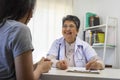 General practitioner taking notes when talking to female patient in hospital. Royalty Free Stock Photo