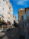 General view of the empty street going up. Construction of a building behind a fence. Graffiti on the walls and fence