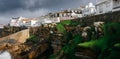 General view of Ericeira beach and houses and sea moss n cliffs under a cloudy winter sky, Portugal. Royalty Free Stock Photo