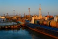 General view of an industrial harbor with moored large ships with masts, barges with cargo, boats in the red light of sunset Royalty Free Stock Photo