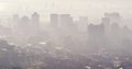 General view of misty modern cityscape with skyscrapers and building site