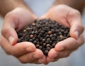 Cupped hands holding black peppercorns