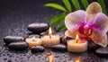 Beautiful spa background with massage stones, candles, pink orchid and drops of waters on black backdrop. Royalty Free Stock Photo