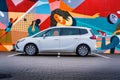 White family MPV Opel Zafira Tourer. A car in front of a colorful wall.