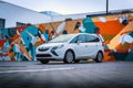 White family MPV Opel Zafira Tourer. A car in front of a colorful wall.