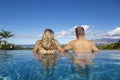 Rear view of handsome couple in an infinity pool looking out tropical island landscape in Hawaii Royalty Free Stock Photo