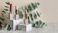 Decorative plaster podiums, lipsticks and eucalyptus branch on beige background with copy space