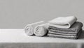 Gray white bed linen, a sheet and two rolled up towels on the table with copy space Royalty Free Stock Photo