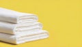 Stack of clean bed sheets on yellow background with copy space